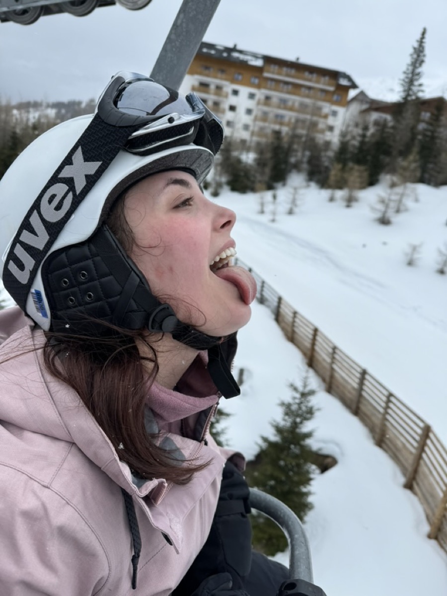 Bella catching snow on her tongue on a ski lift