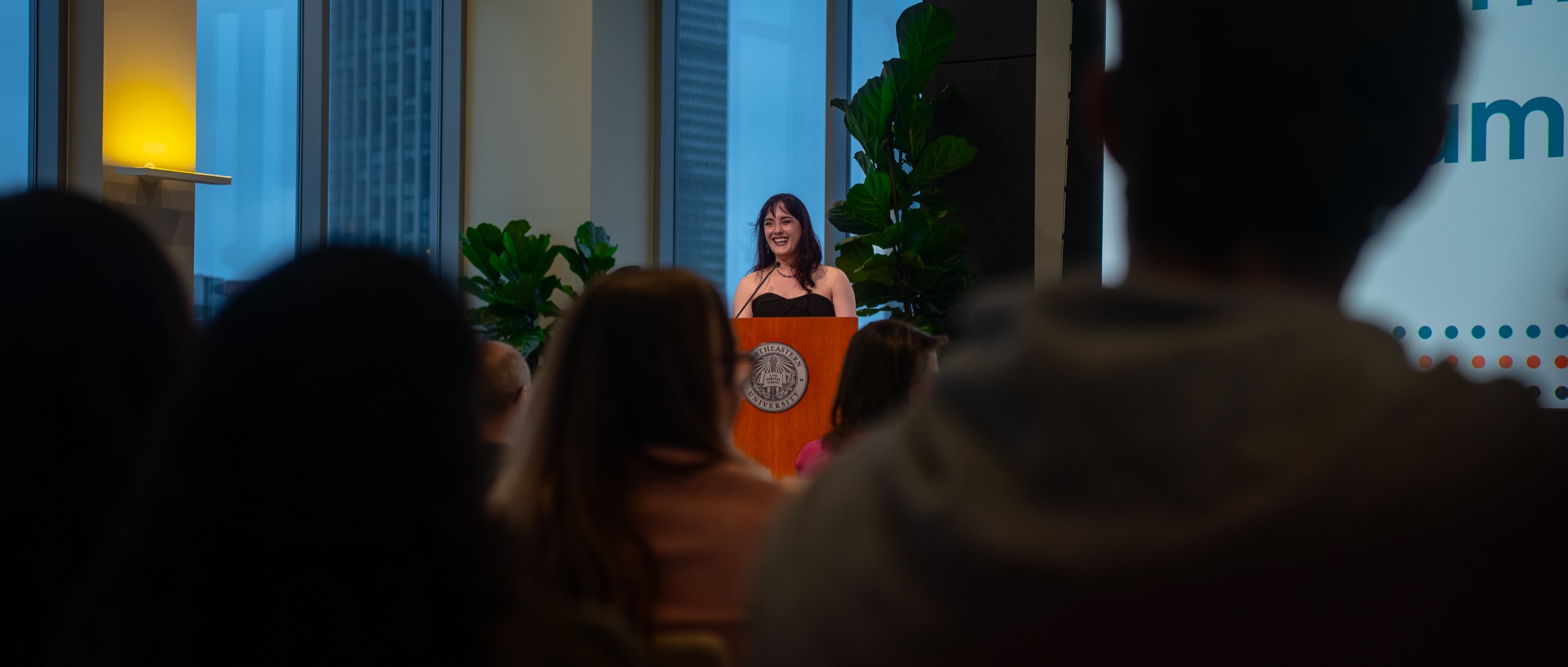 Bella laughing at the podium while hosting Pitch-A-Thon